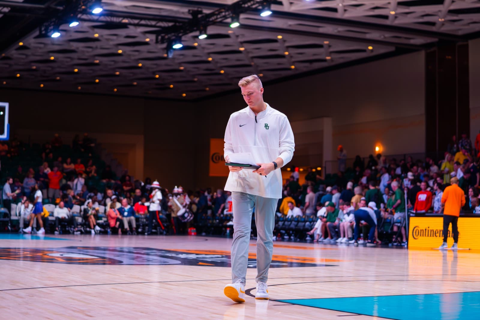 Nolan Mader walking the sideline in an arena before a game